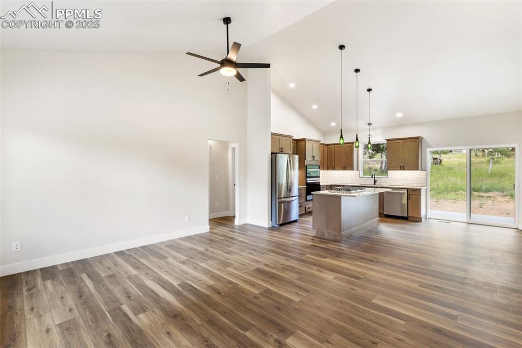 Image 8 of 35: Kitchen with open floor plan, a center island, pendant lighting, high vault
