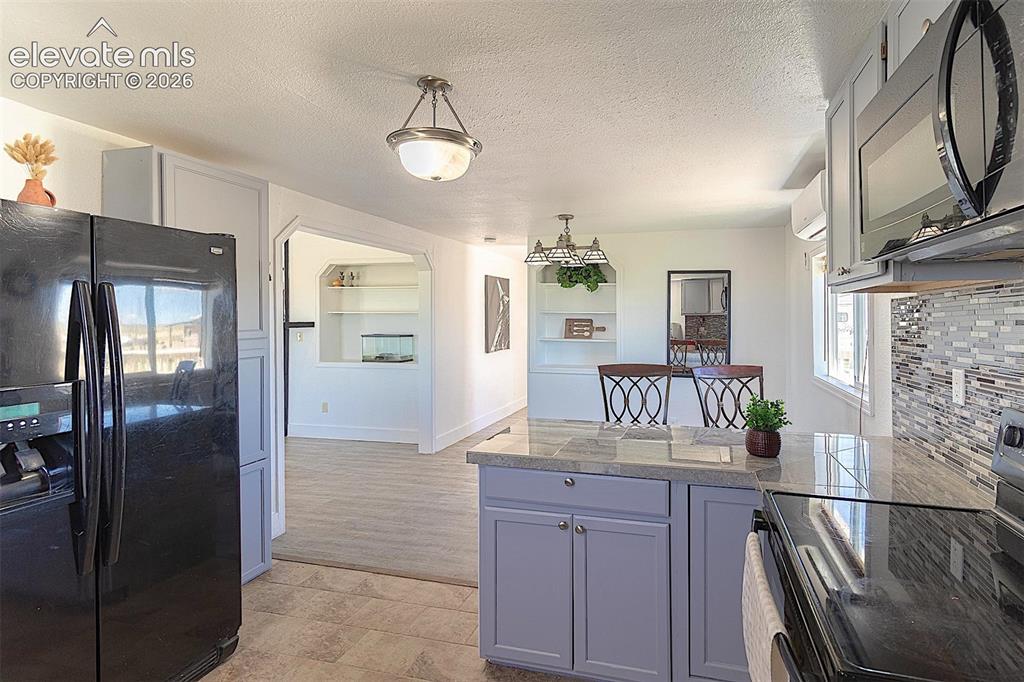 Image 10 of 25: Kitchen featuring black appliances, tile counters, a peninsula, built in fe