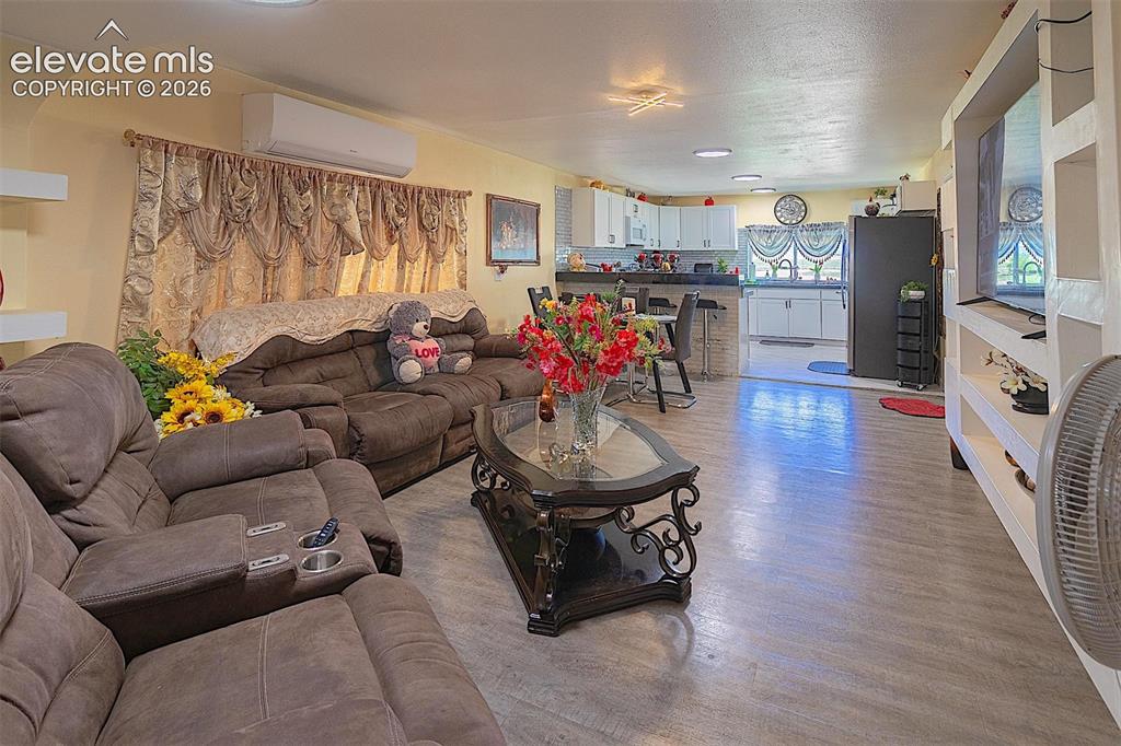 Image 23 of 25: Living room with an AC wall unit and light wood-type flooring