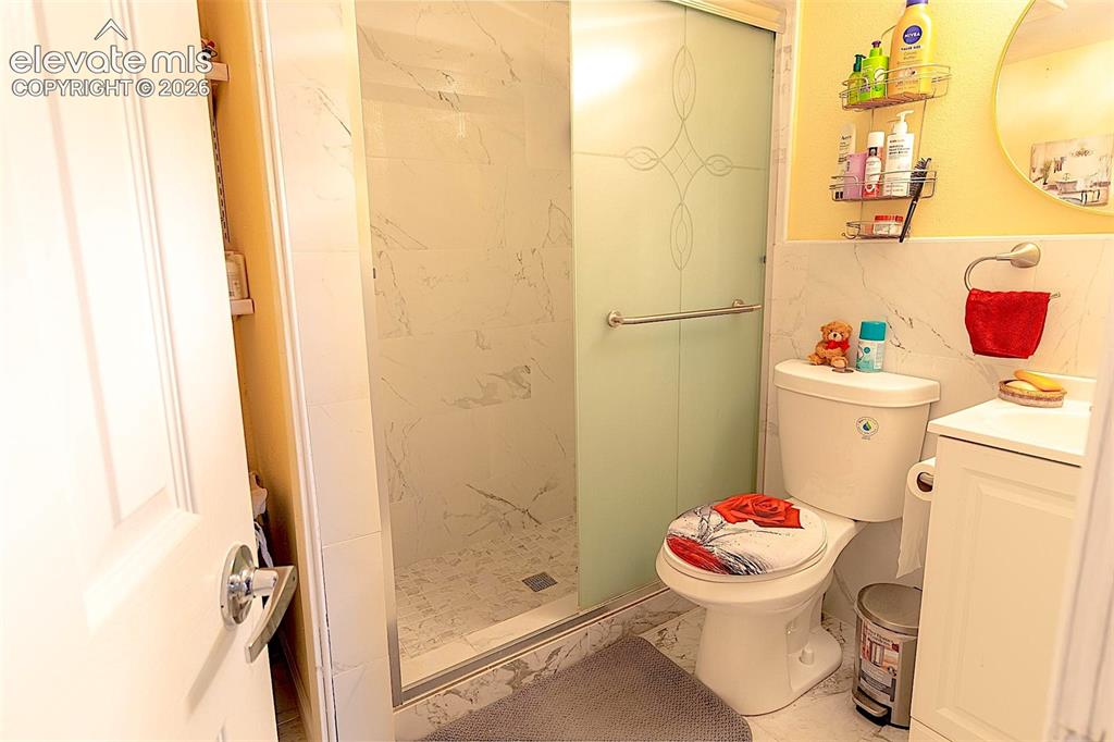 Image 24 of 25: Full bathroom featuring marble finish floors, vanity, toilet, and a shower