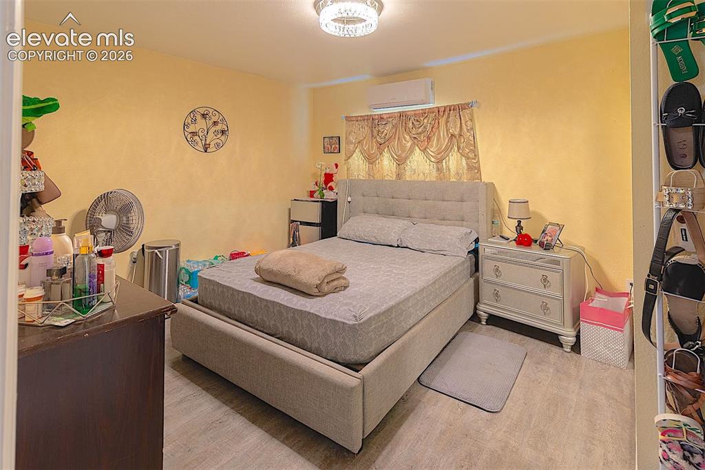 Image 25 of 25: Bedroom featuring a wall mounted air conditioner and wood finished floors