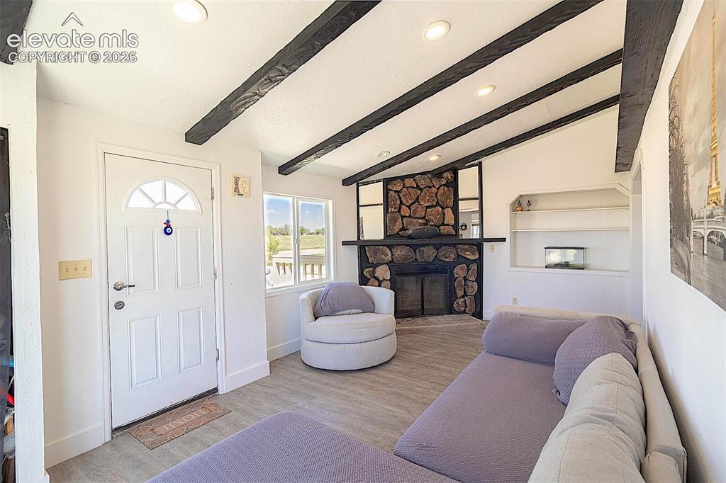 Image 8 of 25: Living area with recessed lighting, a stone fireplace, wood finished floors