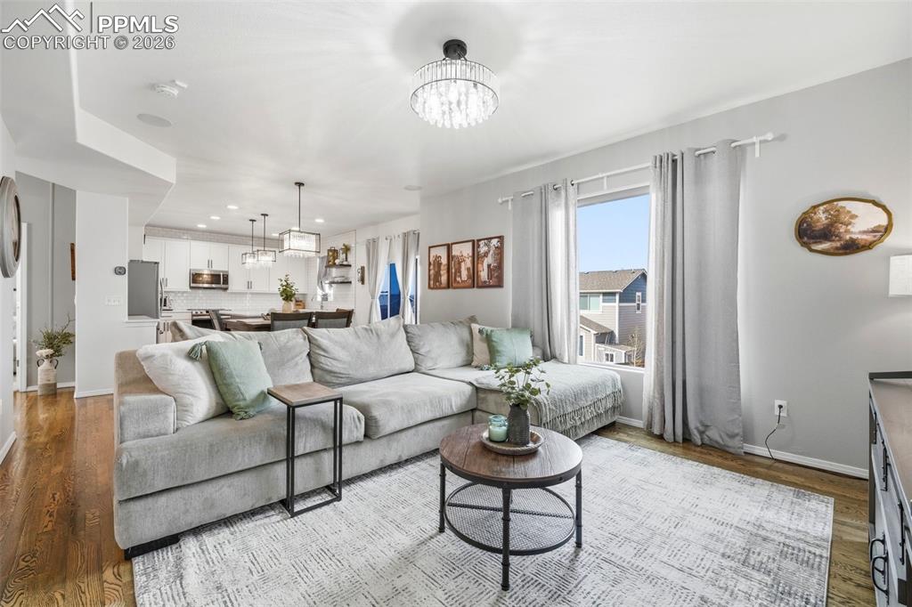 Image 10 of 48: Living room featuring hanging lights and wood finished floors