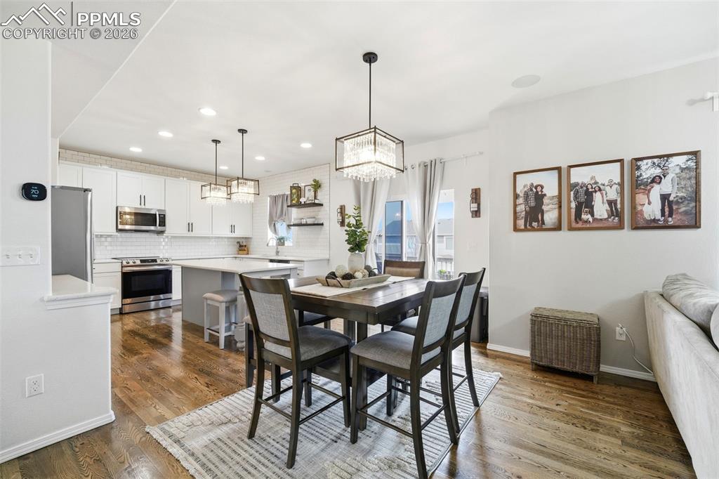 Image 12 of 48: Dining area with dark wood-style floors and suspended lighting
