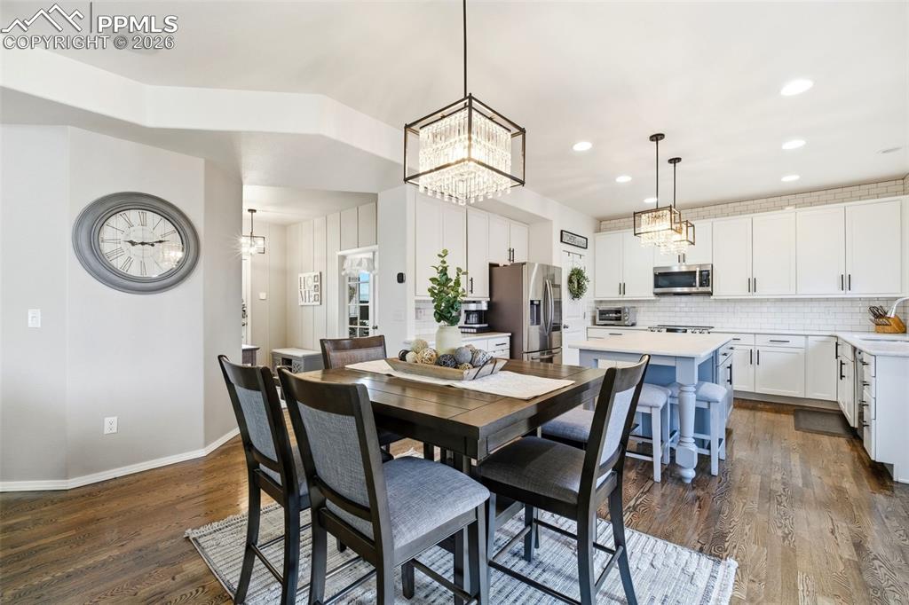 Image 14 of 48: Dining room featuring dark wood-style flooring and hanging lights