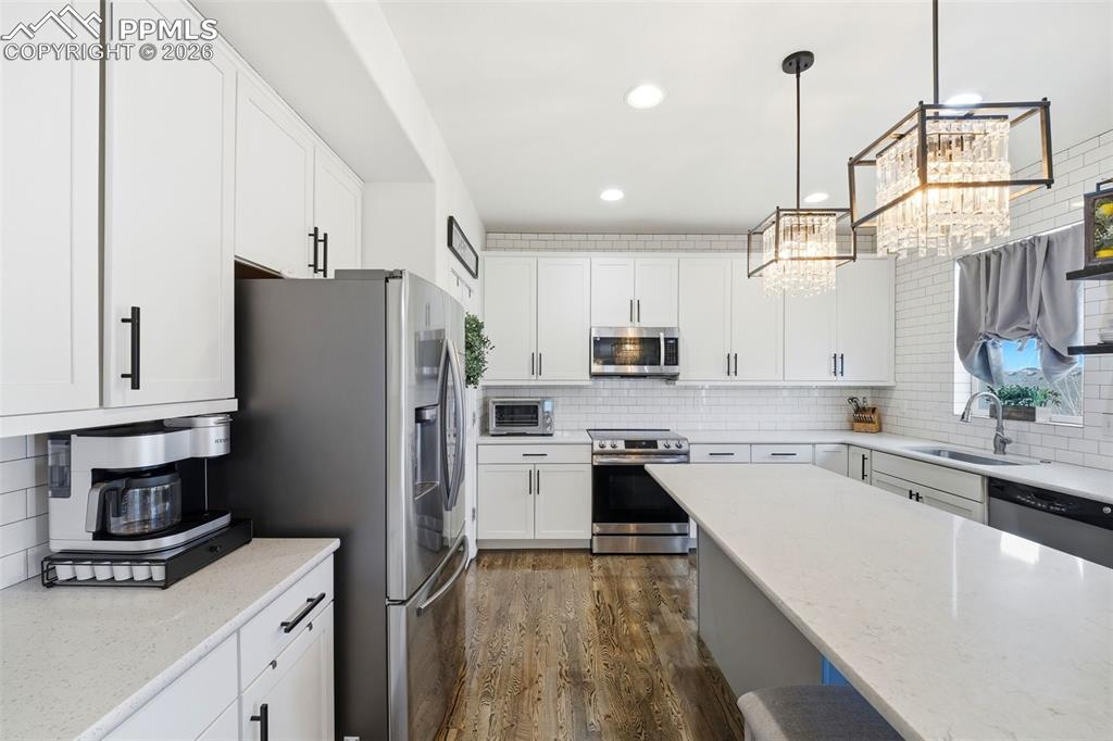 Image 15 of 48: Kitchen with stainless steel appliances, dark wood-style floors, white cabi