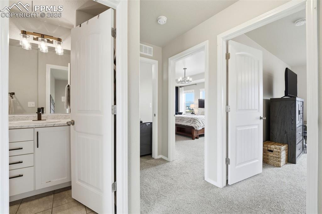 Image 18 of 48: Ensuite bathroom with vanity, light colored carpet, and suspended lighting