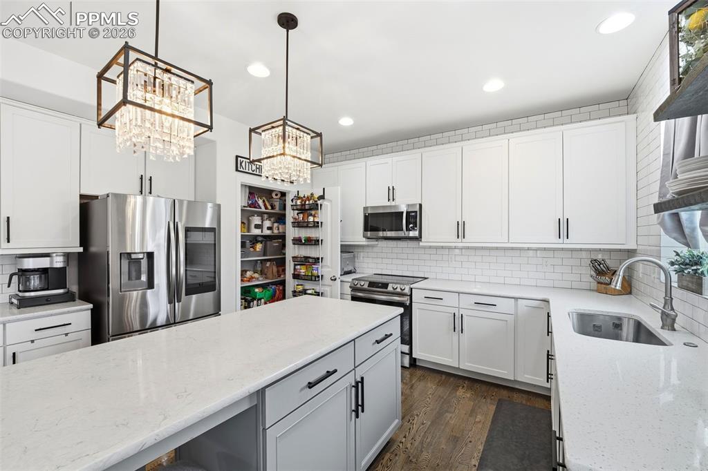 Image 2 of 48: Kitchen with stainless steel appliances, backsplash, light stone countertop