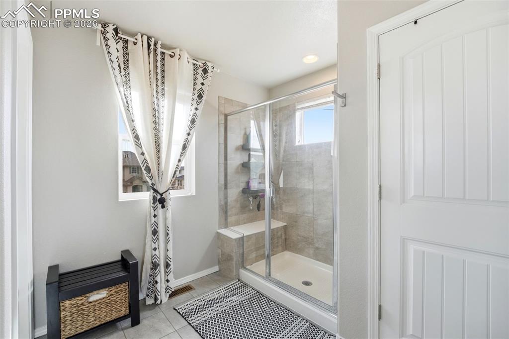 Image 21 of 48: Full bath with a shower stall, light tile patterned floors, and recessed li