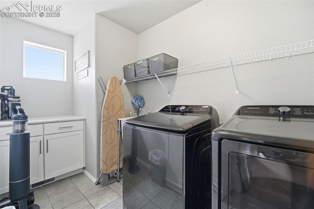 Image 25 of 48: Laundry room with light tile patterned floors, washing machine and clothes