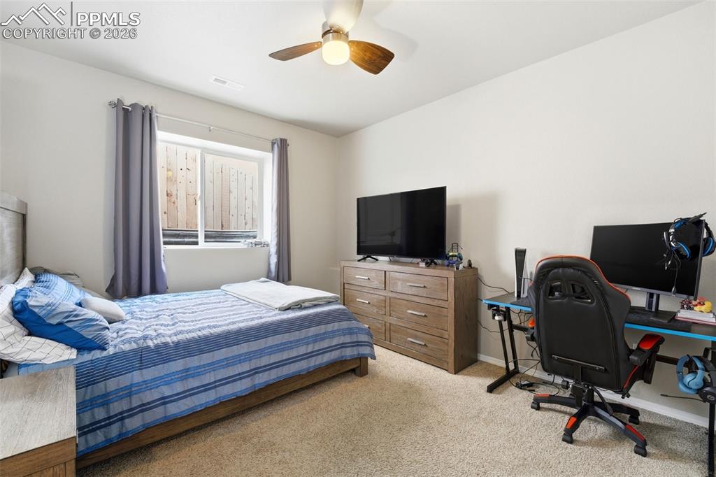 Image 33 of 48: Bedroom featuring an office area, light colored carpet, and ceiling fan