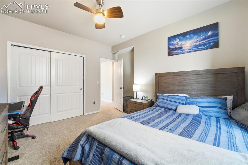Image 34 of 48: Bedroom featuring a desk, light colored carpet, a closet, and a ceiling fan