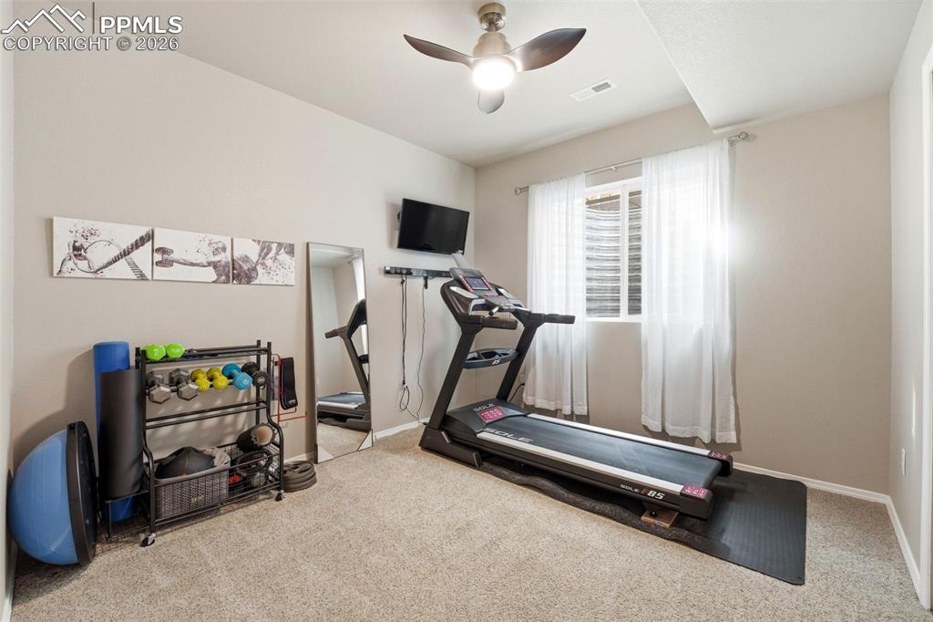 Image 35 of 48: Workout room with light colored carpet and ceiling fan