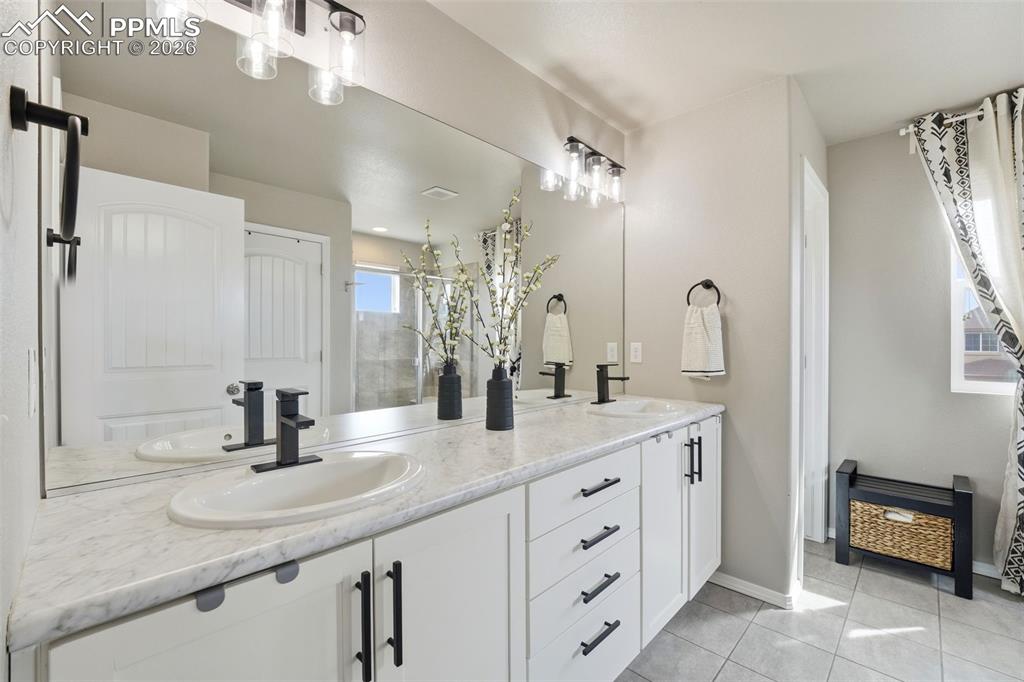 Image 4 of 48: Bathroom with double vanity, a shower stall, and light tile patterned floor