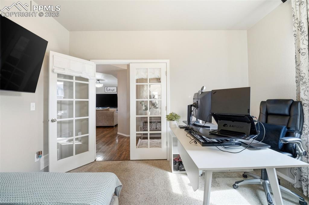 Image 8 of 48: Bedroom featuring a desk, french doors, and light carpet