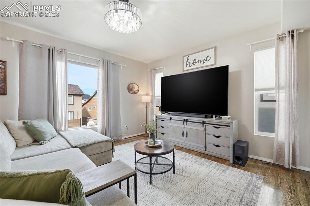 Image 9 of 48: Living area with wood finished floors and a chandelier