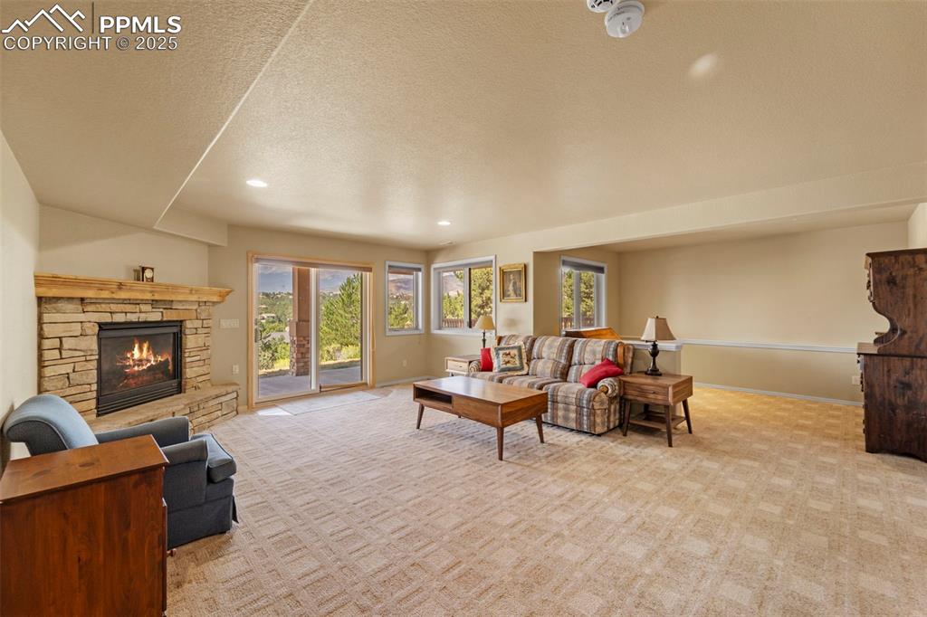 Image 13 of 33: Lower level family room with open office area, fireplace, and walkout to co
