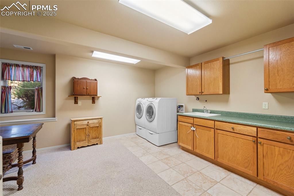 Image 19 of 33: Lower level laundry room with sink and lots of storage
