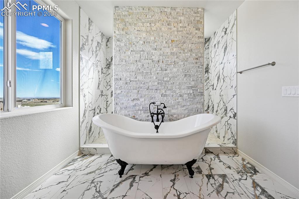 Image 13 of 36: Bathroom with a freestanding tub, tile walls, and marble finish flooring