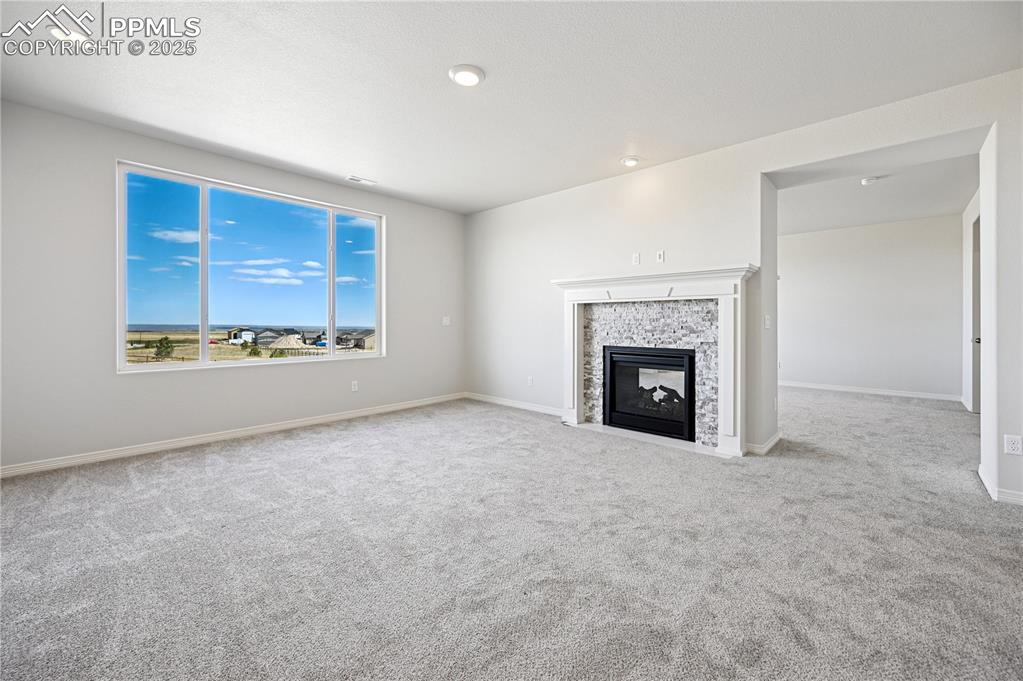 Image 16 of 36: Unfurnished living room with light carpet, a tiled fireplace, and recessed 
