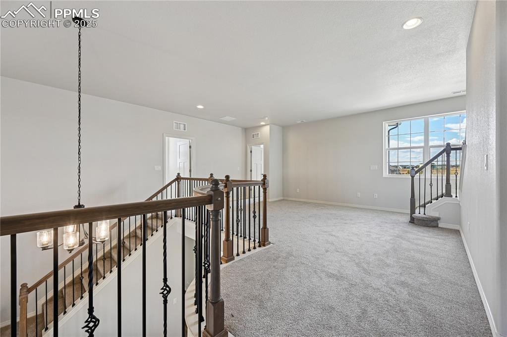 Image 17 of 36: Hall with carpet floors, recessed lighting, stairway, a chandelier, and an 