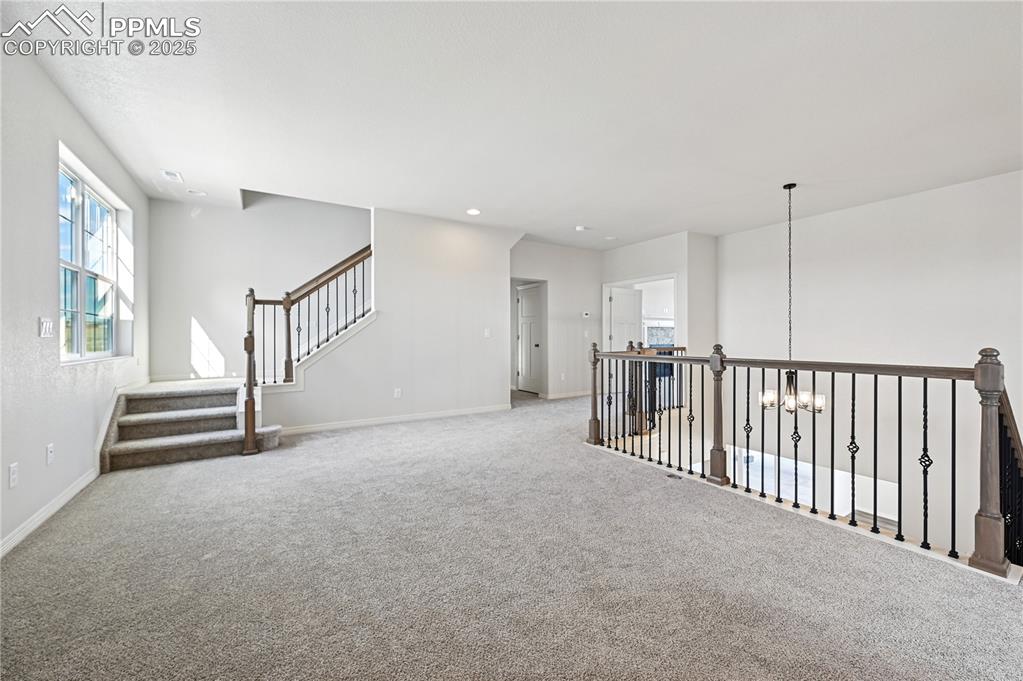 Image 18 of 36: Carpeted empty room featuring stairs, recessed lighting, and a chandelier