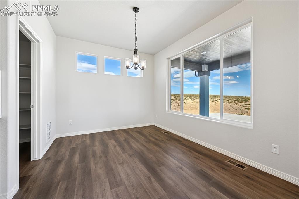 Image 21 of 36: Unfurnished dining area featuring dark wood-style floors and a chandelier