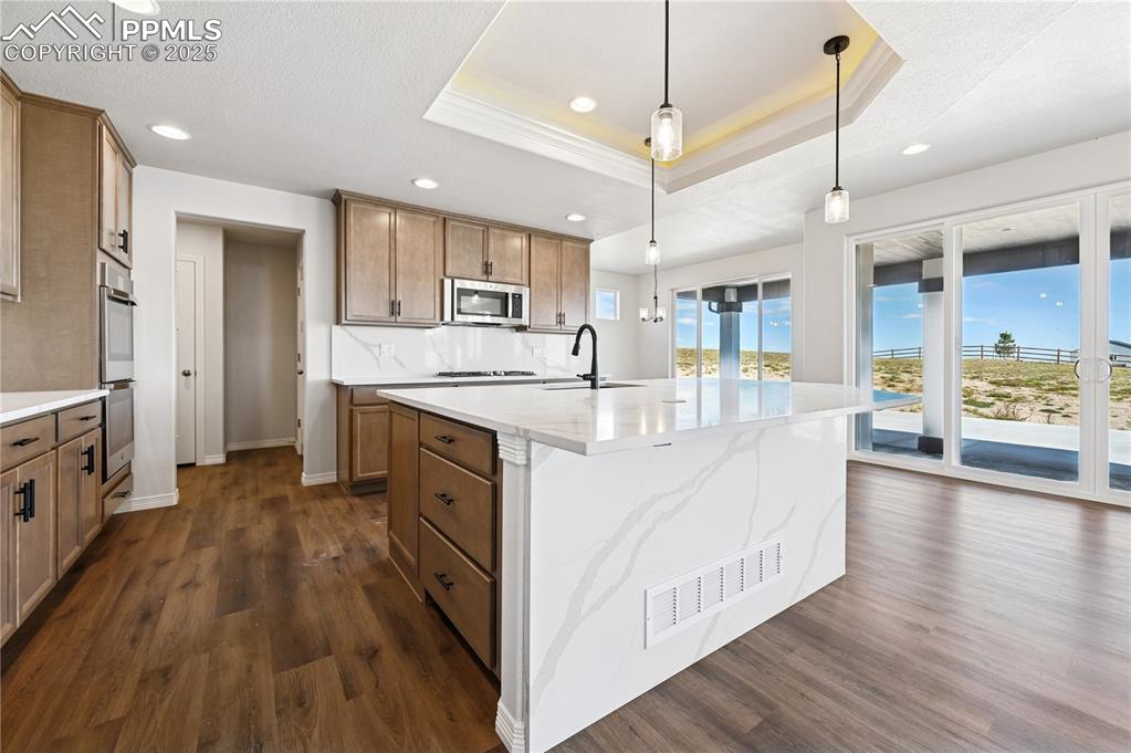 Image 24 of 36: Kitchen with brown cabinetry, recessed lighting, hanging light fixtures, a 