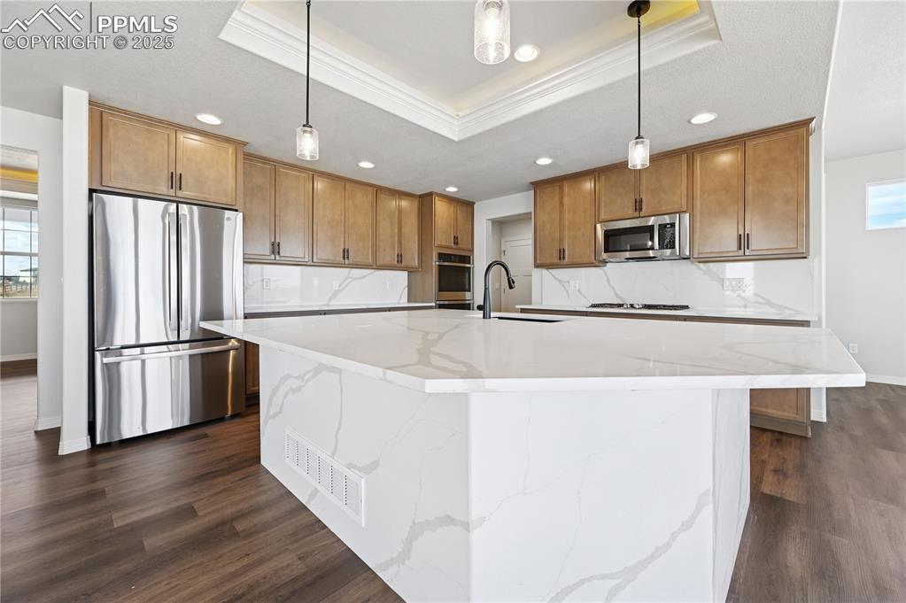 Image 26 of 36: Kitchen with brown cabinets, appliances with stainless steel finishes, tast