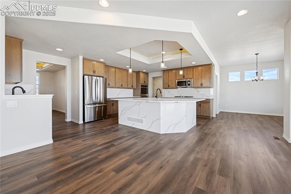 Image 27 of 36: Kitchen with brown cabinets, appliances with stainless steel finishes, deco