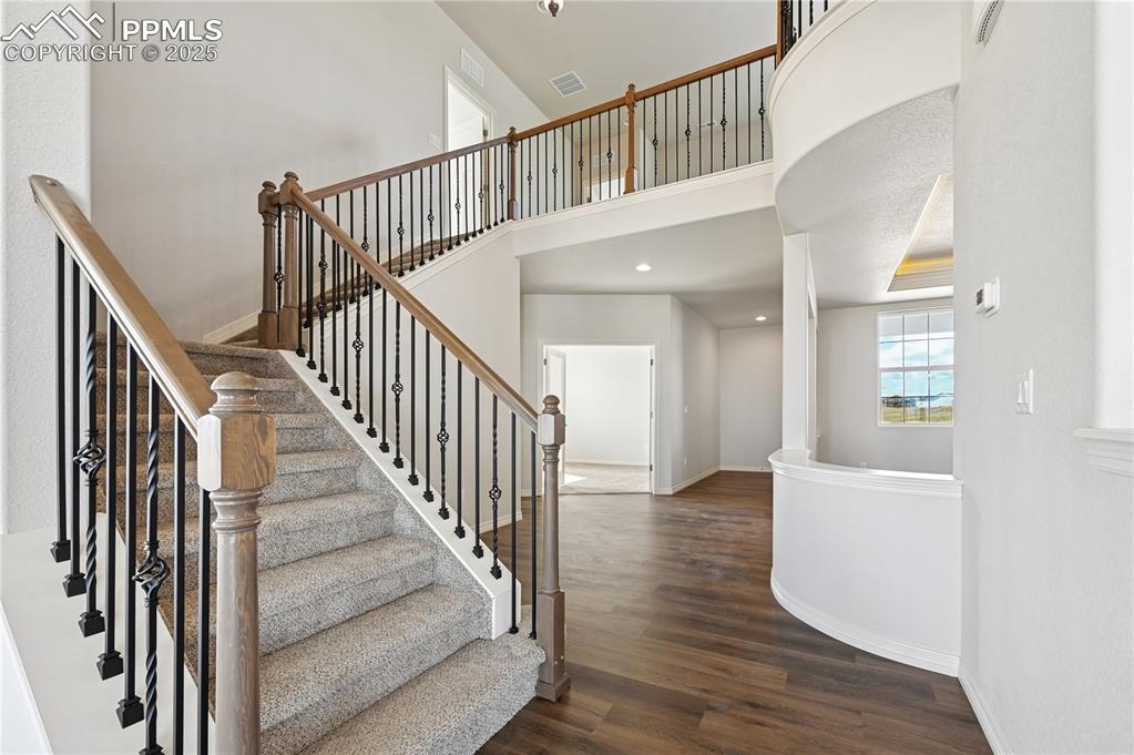 Image 30 of 36: Staircase featuring a high ceiling, wood finished floors, and recessed ligh