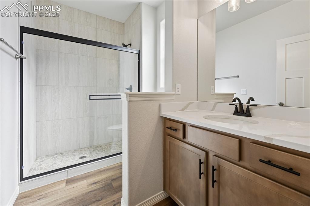 Image 31 of 36: Full bathroom featuring a shower stall, vanity, and light wood finished flo