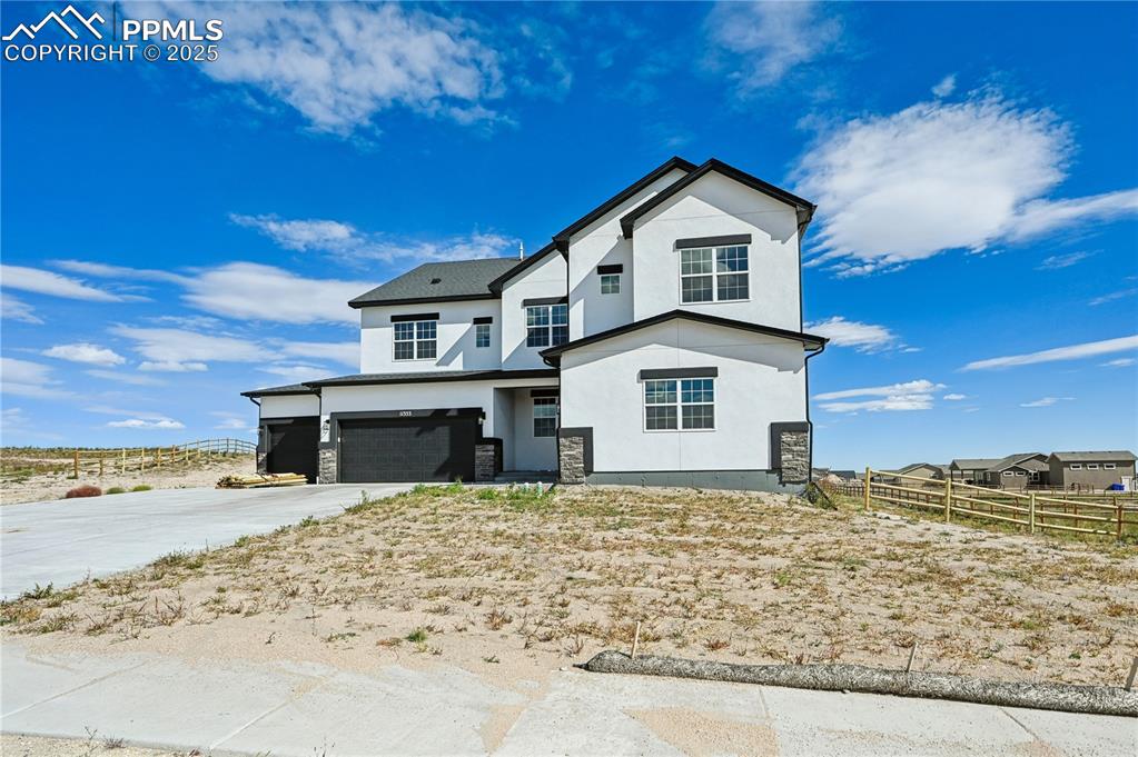 Image 35 of 36: View of front of property featuring a garage, stucco siding, driveway, and 