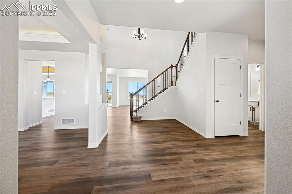 Image 36 of 36: Entryway with dark wood-style floors, stairway, and a chandelier