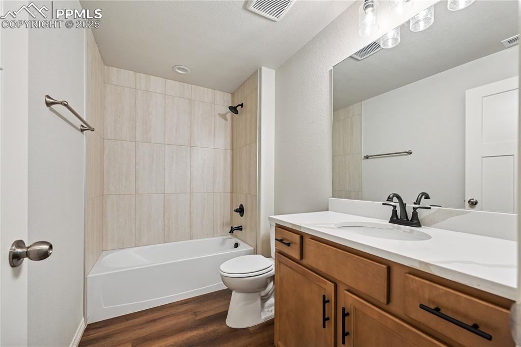 Image 5 of 36: Bathroom featuring shower / bath combination, vanity, and dark wood-style f