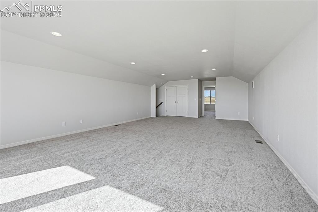 Image 6 of 36: Additional living space with light colored carpet, lofted ceiling, and rece