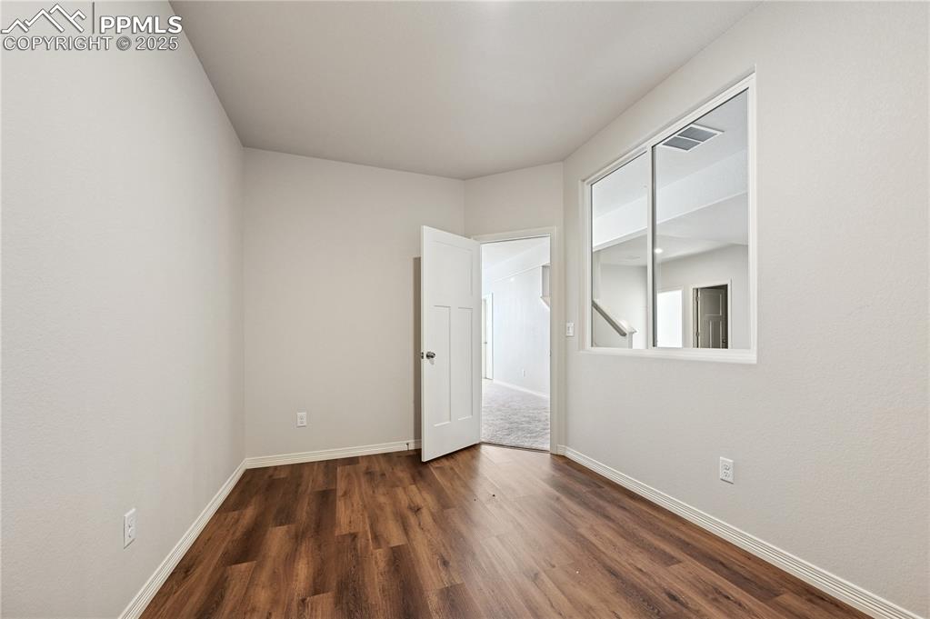 Image 7 of 36: Unfurnished room featuring dark wood-type flooring and baseboards