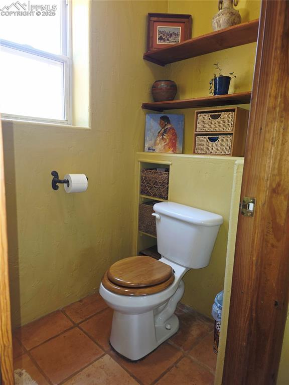 Image 12 of 42: Bathroom with toilet and dark tile patterned flooring