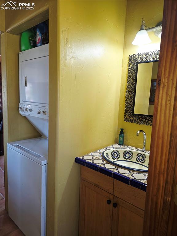 Image 14 of 42: Laundry room with stacked washing machine and dryer and a textured wall
