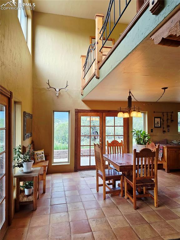 Image 5 of 42: Dining room featuring a towering ceiling and stone tile floors