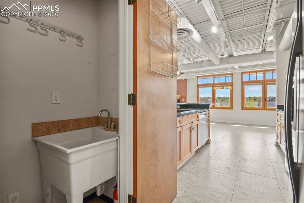 Image 15 of 50: Large broom closet with mop sink conveniently located adjacent to the kitch