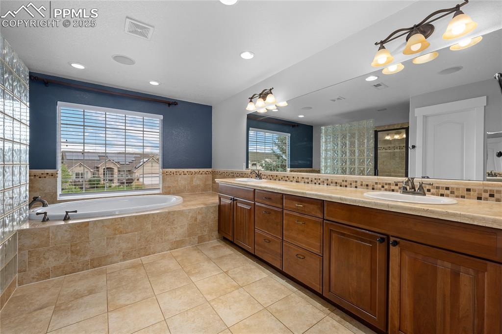 Image 12 of 24: Full bathroom featuring a garden tub, light tile patterned floors, double v