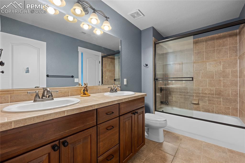 Image 14 of 24: Jack and Jill Bathroom with enclosed tub / shower combo, light tile pattern