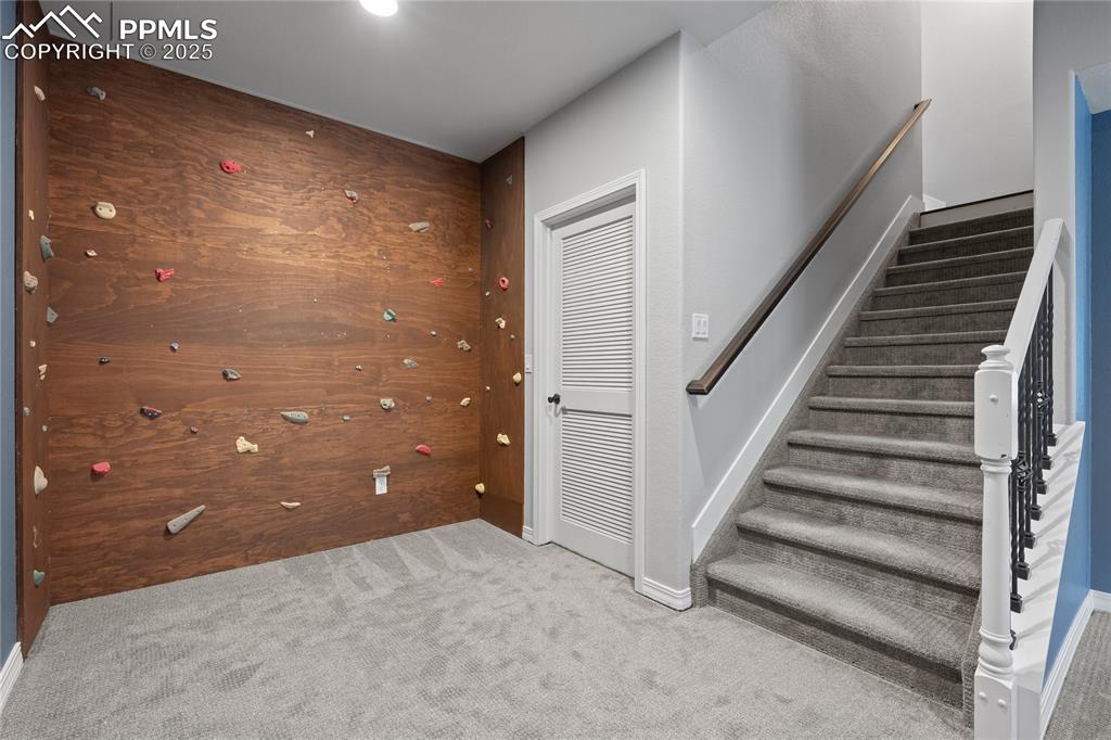 Image 16 of 24: Staircase  and climbing wall and carpet floor.