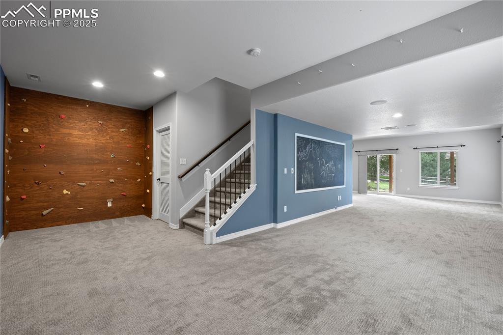 Image 17 of 24: Basement family room with carpet floors, stairs and recessed lighting