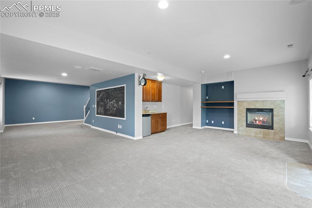 Image 19 of 24: Basement family room featuring a tile fireplace, recessed lighting, wet bar