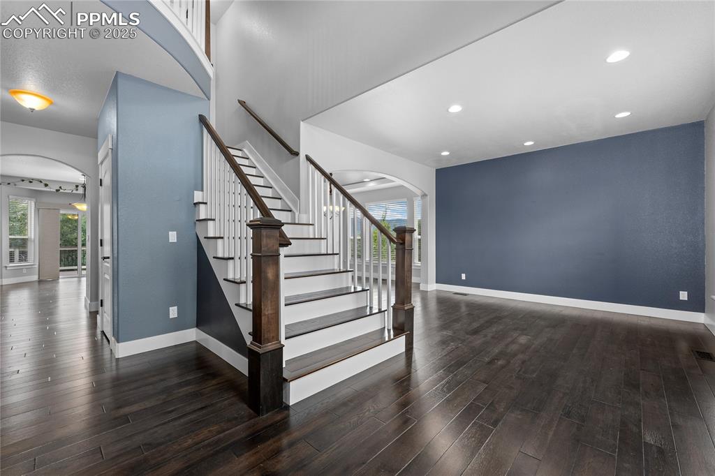 Image 3 of 24: Stairs featuring arched walkways, wood finished floors, and recessed lighti