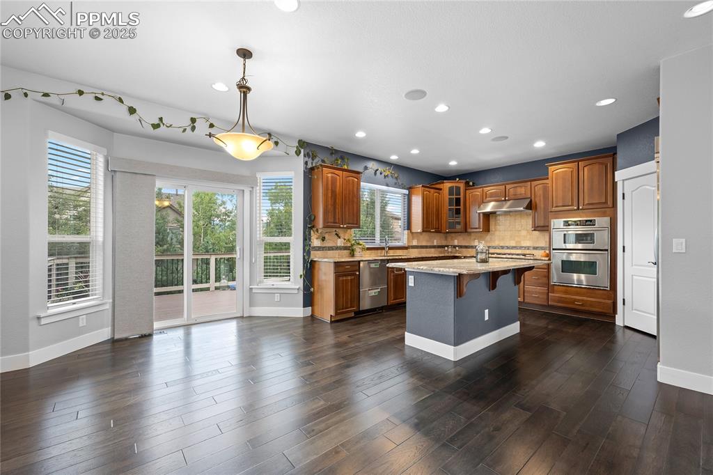 Image 6 of 24: Kitchen with a breakfast bar, tasteful backsplash, glass insert cabinets, l