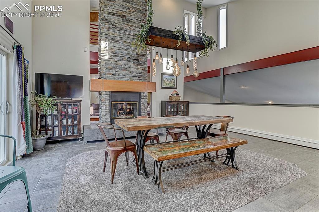 Image 16 of 41: Dining space with a high ceiling and a stone fireplace
