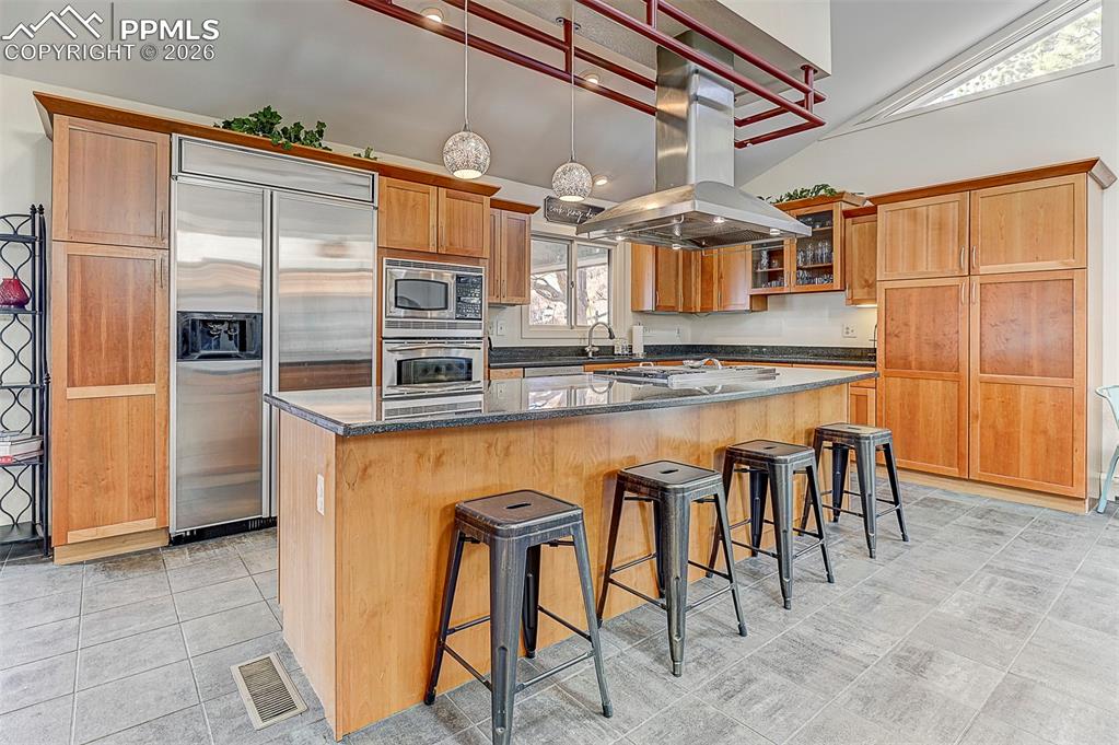 Image 18 of 41: Kitchen featuring built in appliances, a breakfast bar, island range hood, 